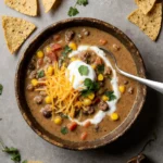 Creamy taco soup in a bowl with toppings and tortilla chips.