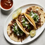 Birria tacos with consommé and lime