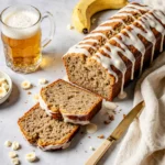 Banana beer bread with white chocolate drizzle, sliced and served with a cold beer.